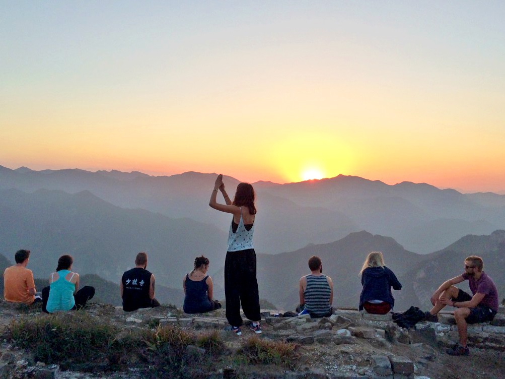 Reisegruppe beobachtet Sonnenuntergang auf dem Berggipfel